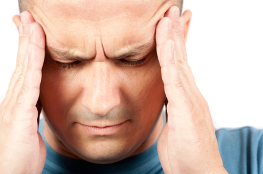 Man putting his hands on his head and looking in pain to represent a headache.